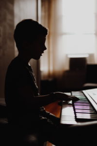 Boy playing piano - photo by Kelly Sikkema